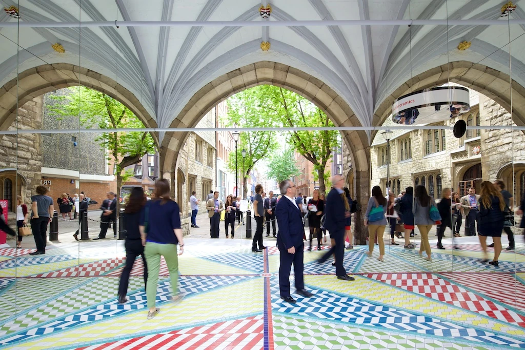 The public moving through the mirrored arch and patterned floor.