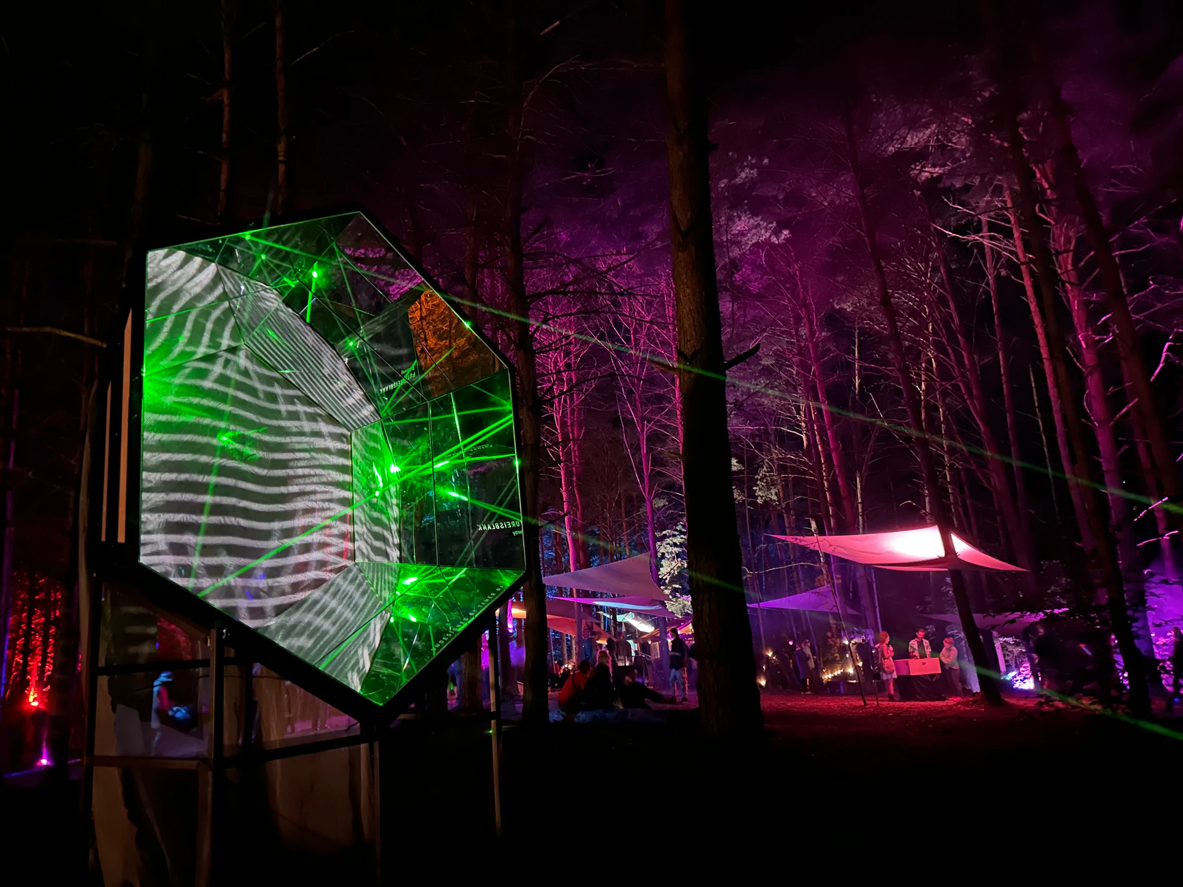 Green projections moving across Gateway Mini in the red and violet-lit forest
