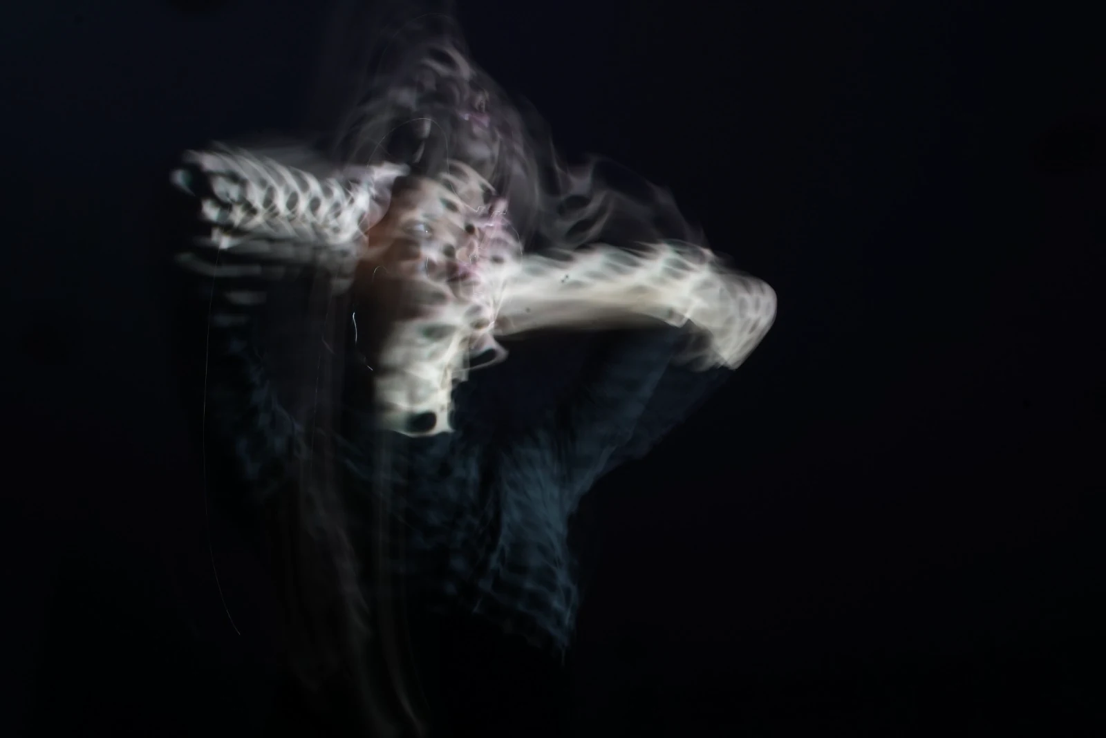 A moving figure dissolving into traces of white projected light
