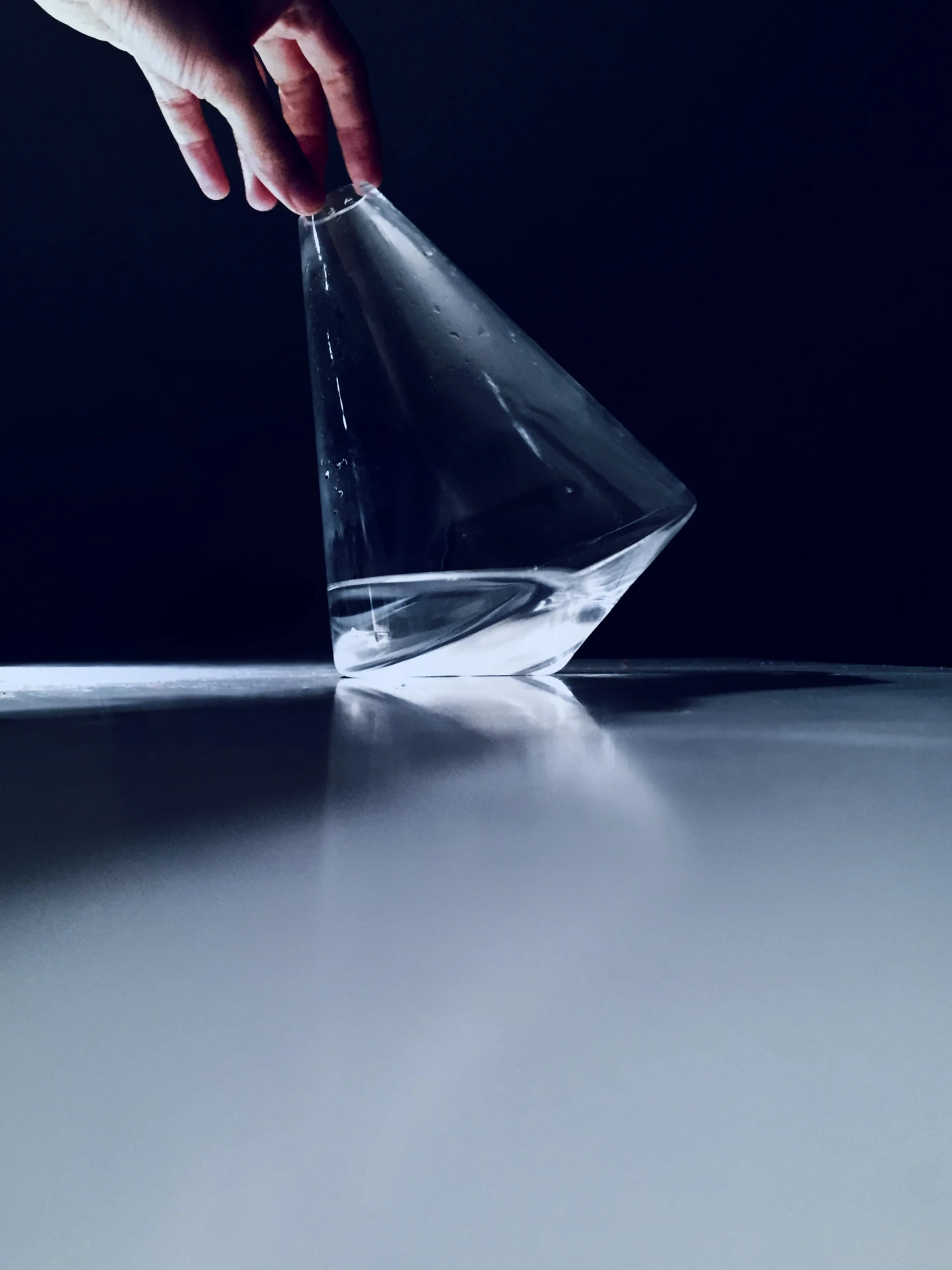 A hand lifting the Omnia jug in blue studio light