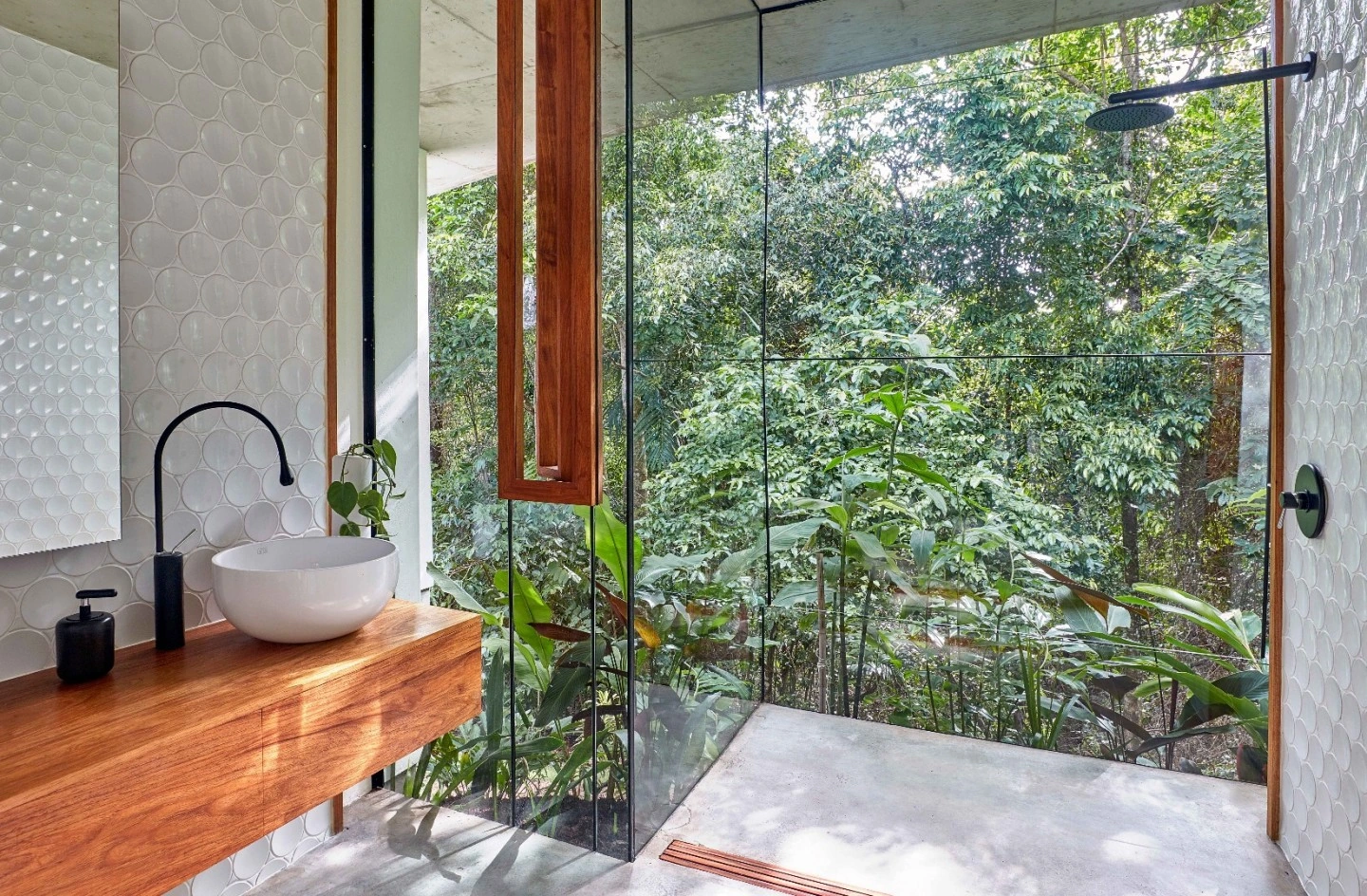Dot tiled bathroom and timber vanity beside rainforest windows