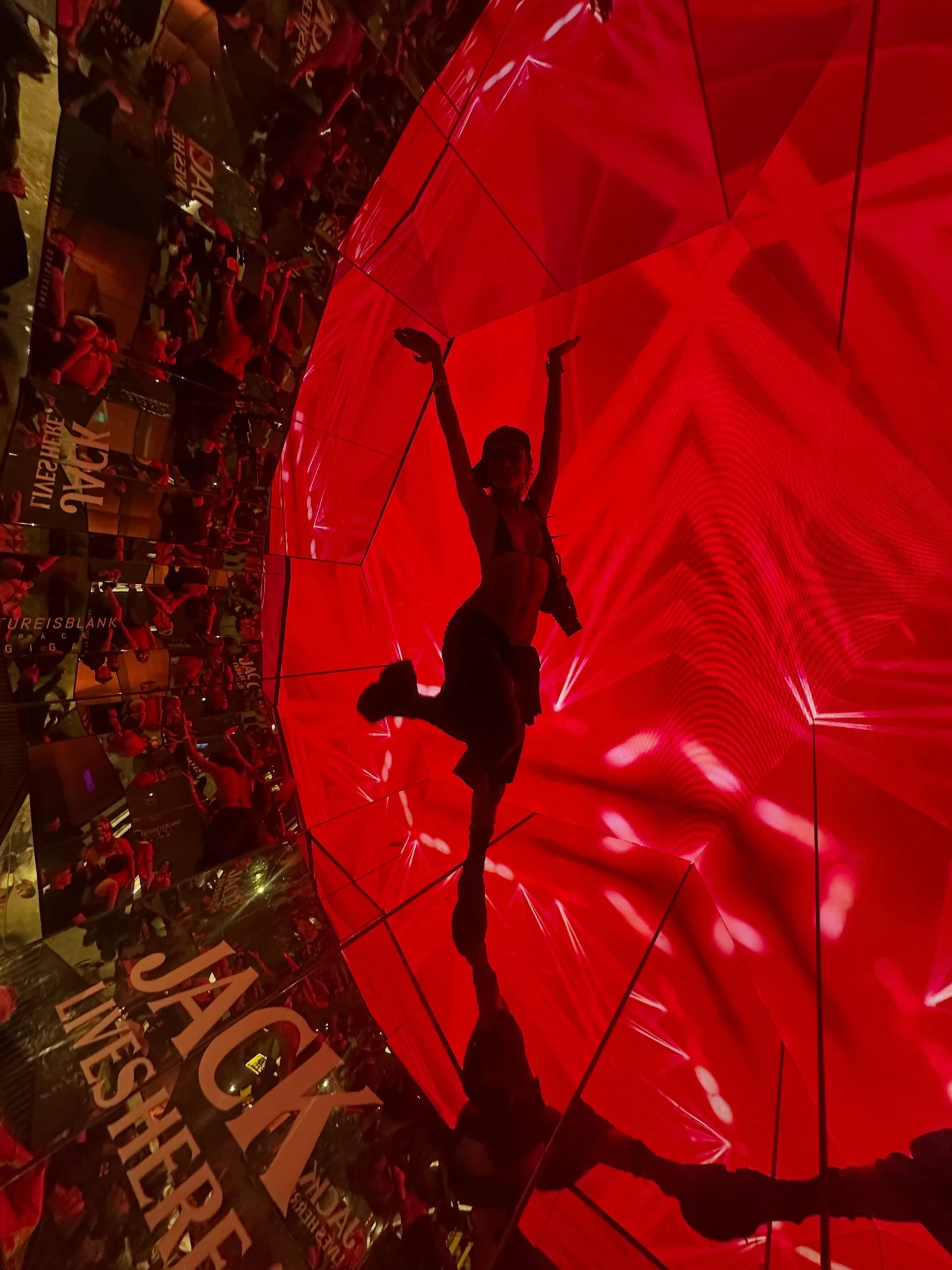 A visitor posing inside red projections and mirrored geometry at a Jack Lives Here concert