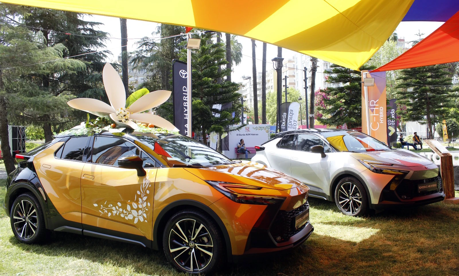 The blossom-topped orange Toyota C-HR and a white C-HR beneath colourful carnival canopies