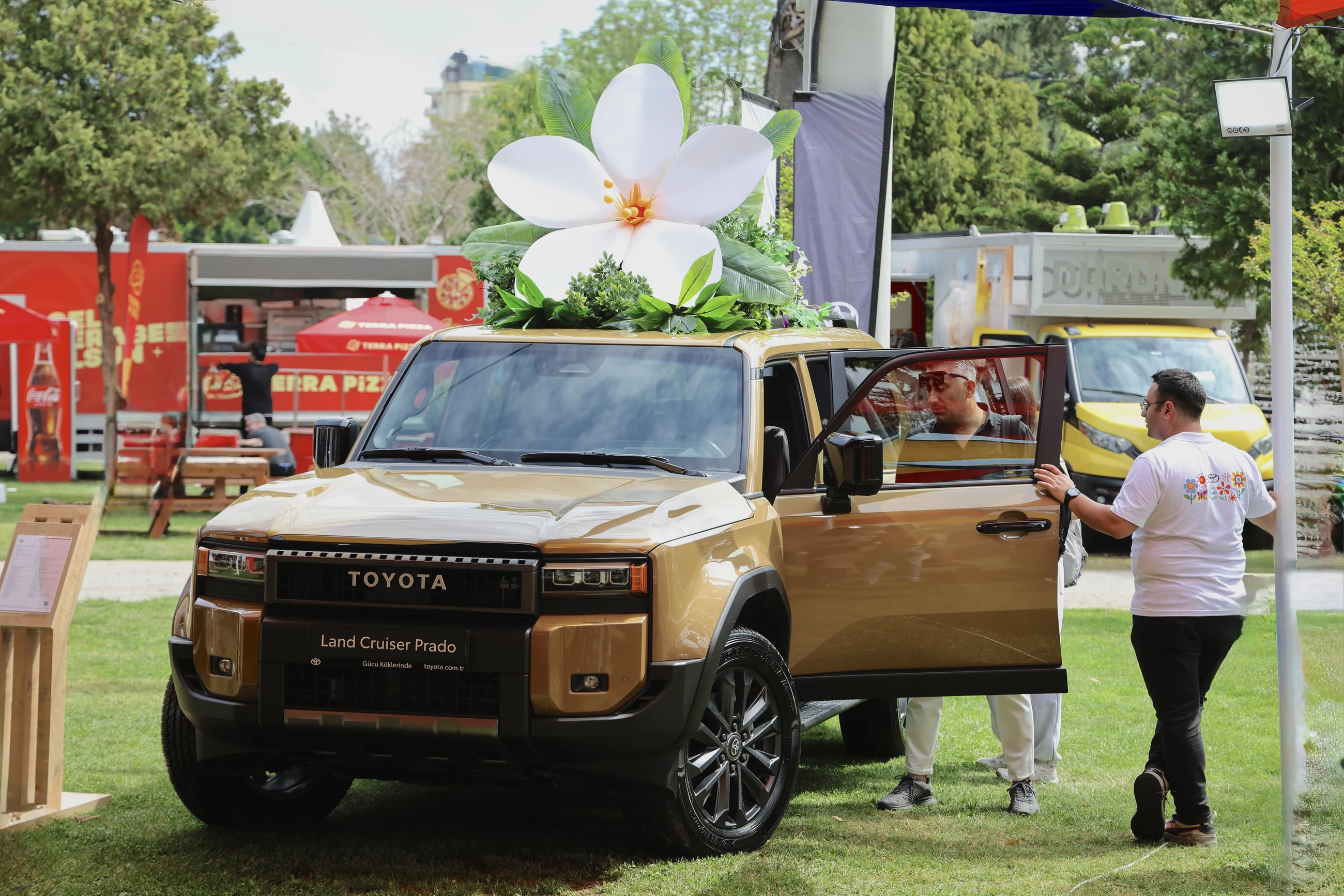 The blossom-topped Land Cruiser Prado at the pavilion with visitors beside the open door