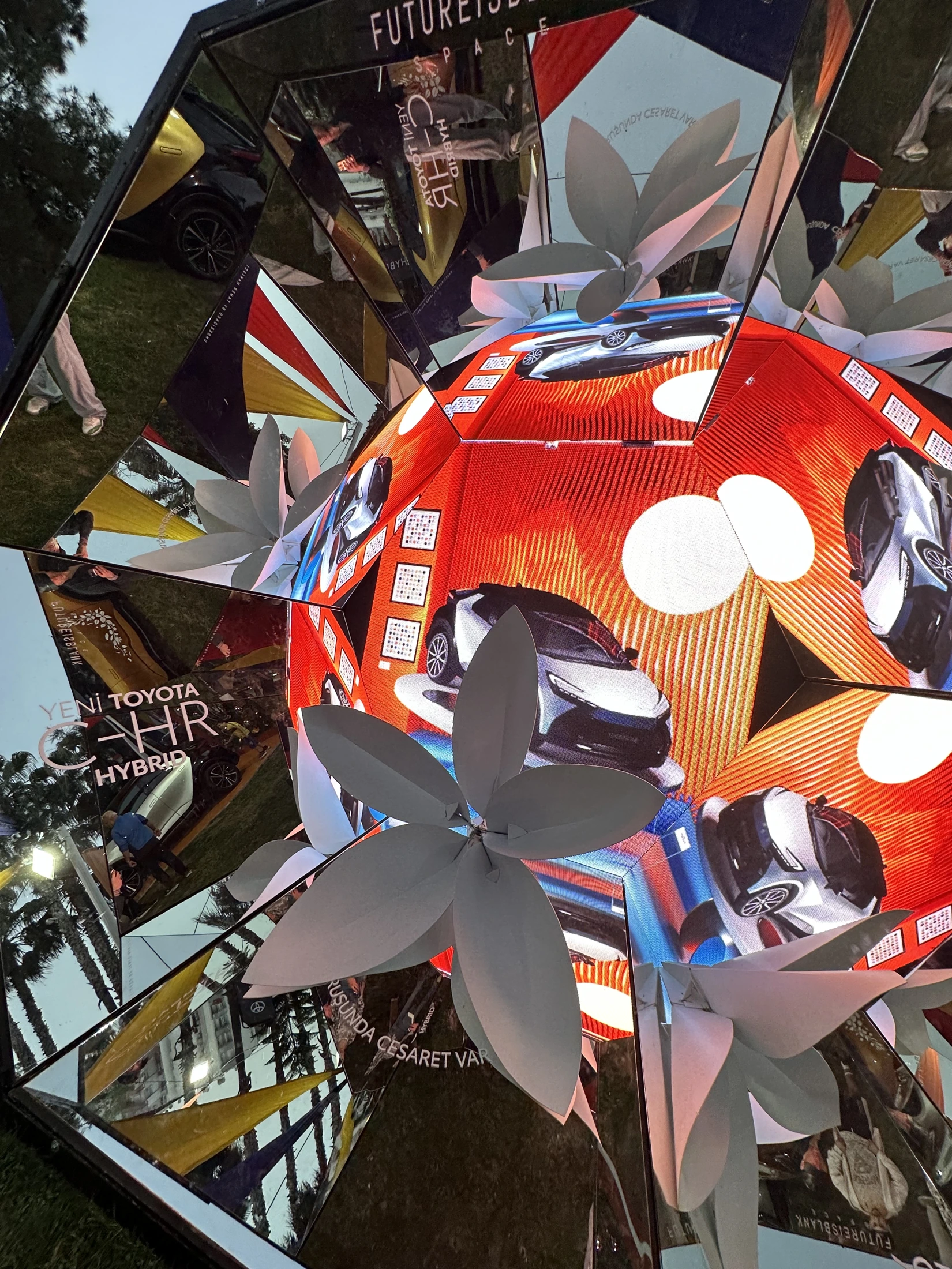 The giant blossom, car and carnival colours reflected inside Futureisblank Space